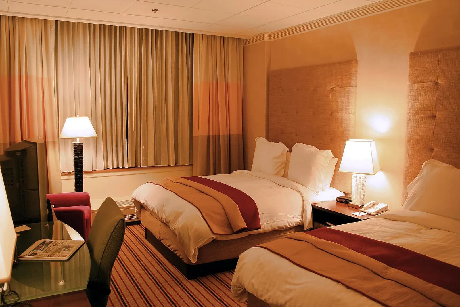 Hotelzimmer mit warmem Licht, Nachttischlampen und frisch bezogenen Betten